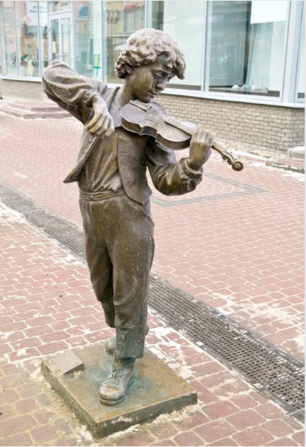 Sculpture of a boy playing the violin on a street
